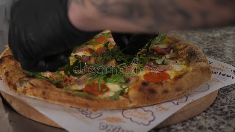 Uno chef che mette l'rucola sulla pizza prima di servire una pizzeria italiana tradizionale video d archivio