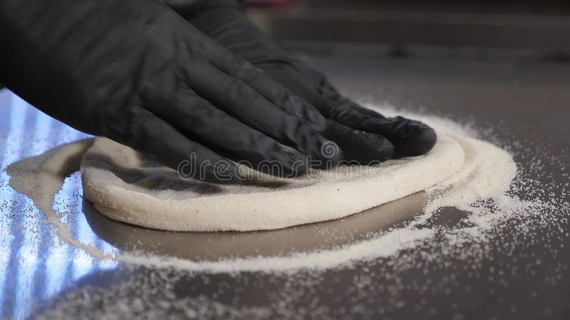 Uno chef in guanti con le mani che tirano fuori un impasto con le mani video d archivio