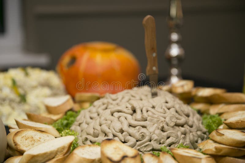 Uno spuntino insolito su un grande piatto, nel centro di cui è una montagna di patè sotto forma di cervelli con un coltello pugna fotografia stock libera da diritti