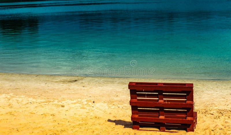 Unreal picture of the end of summer at a lake with an empty beach and a deck chair made of europallets