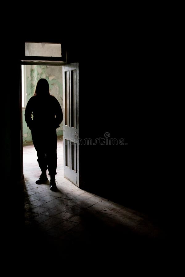 Unrecognised person standing alone on the open door of an abandoned building