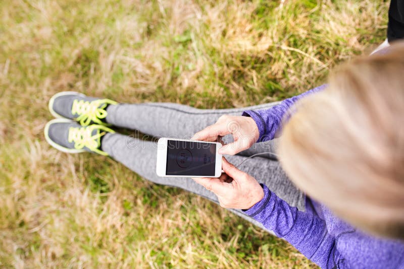 Unrecognizable active senior runner in nature with smart phone. stock photo Unrecognizable active senior runner in nature with smart phone. stock photo