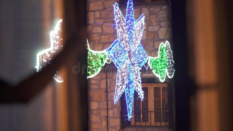 Unrecognizable blurred man raising blinds opening glass door to balcony on Christmas eve. Colorful illuminated New Year