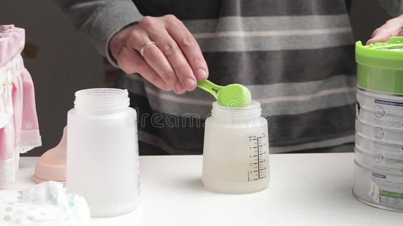 Unrecognizable man preparing baby bottle of powdered milk stock footage