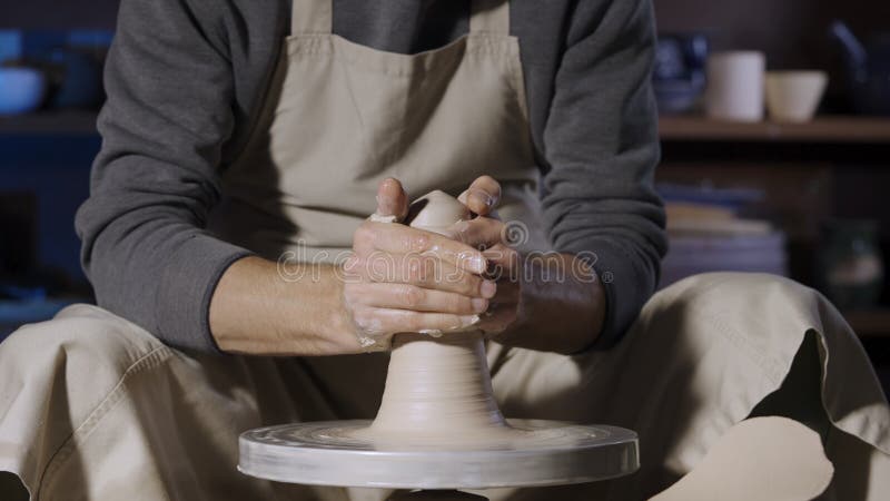 A detailed image of a pair of hands delicately sculpting clay on a potter's  wheel during a soft-lit evening in a pottery studio, captured with a medium  format camera using a macro