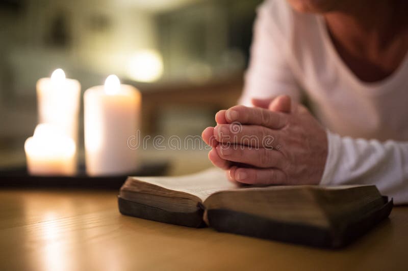 Unrecognizable senior woman praying, hands clasped together on h