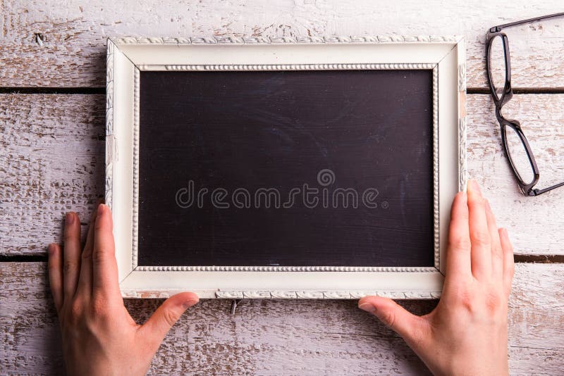 Unrecognizable woman holding empty picture frame, eyeglasses. St