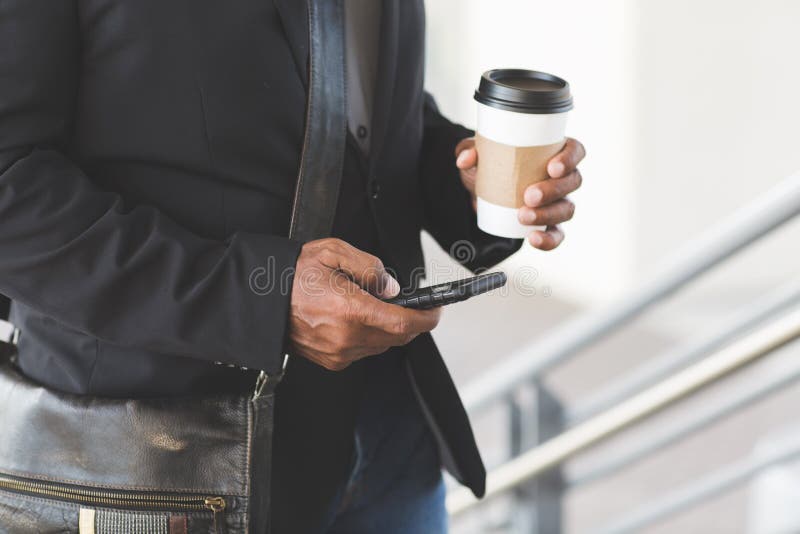 African American businessman drinking coffee and texting.