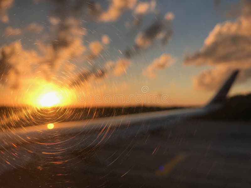 Unscharfe Leuchtorangesonne und der Flügel der Flugzeuge während der Dämmerung auf der Rollbahn gegen das Waldschattenbild lizenzfreies stockfoto Unscharfe Leuchtorangesonne und der Flügel der Flugzeuge während der Dämmerung auf der Rollbahn gegen das Waldschattenbild lizenzfreies stockfoto