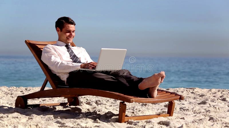 Unstressed businessman using laptop on the beach