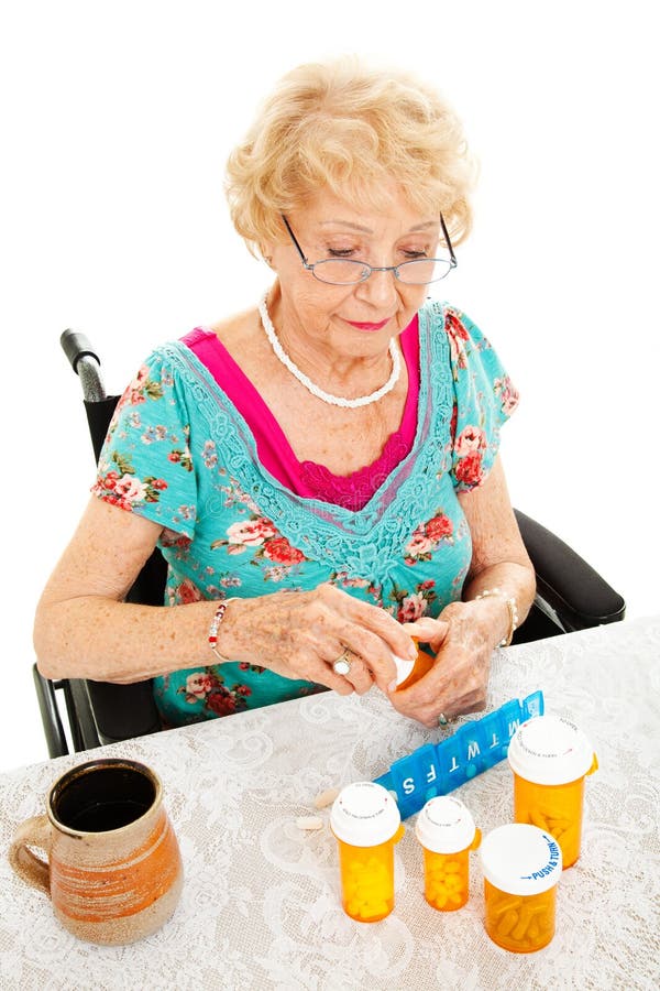 Disabled senior woman in a wheelchair, counting out her medications for the week. White background. Disabled senior woman in a wheelchair, counting out her medications for the week. White background.