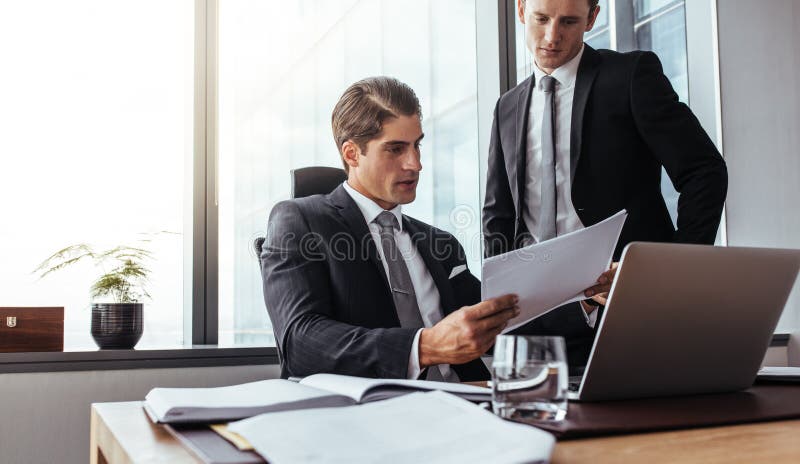 Unternehmensgeschäftsleute, die Papiere im Büro lesen lizenzfreie stockfotografie Unternehmensgeschäftsleute, die Papiere im Büro lesen lizenzfreie stockfotografie