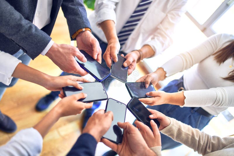 Unternehmensgruppe, die mit Smartphone im Büro mit Händen zusammensteht und Symbol macht lizenzfreies stockbild
