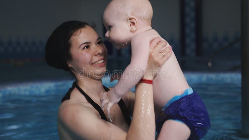 Unterrichtende Babyschwimmen im Pool Eine Mutter unterrichtet ihr Baby zu schwimmen