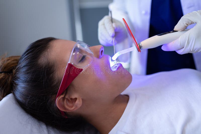 Untersuchungspatient des weiblichen Zahnarztes mit zahnmedizinischem kurierendem Licht in der Klinik stockfoto Untersuchungspatient des weiblichen Zahnarztes mit zahnmedizinischem kurierendem Licht in der Klinik stockfoto