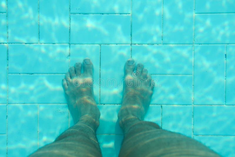 Unterwasserfoto, Unterseite des Swimmingpools mit blauen Fliesen, Mannbeine, die auf ihm stehen lizenzfreie stockfotografie Unterwasserfoto, Unterseite des Swimmingpools mit blauen Fliesen, Mannbeine, die auf ihm stehen lizenzfreie stockfotografie