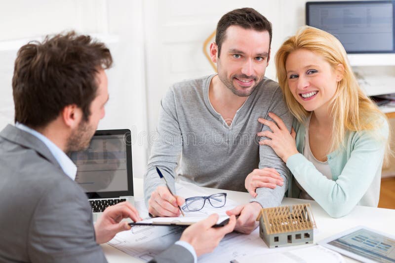 Unterzeichnender Vertrag der jungen attraktiven Paare mit Immobilienagentur stockfoto Unterzeichnender Vertrag der jungen attraktiven Paare mit Immobilienagentur stockfoto