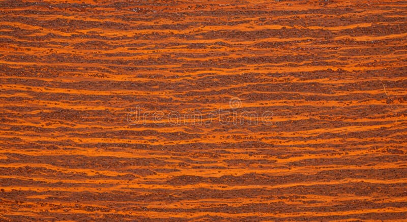 Abstract pattern composed of wavy, horizontal lines in shades of rust, orange, and brown. The texture resembles that of weathered metal with a layered appearance. This design evokes a sense of natural erosion or striations seen in geological formations. The alternating colors enhance the visual depth and texture, reminiscent of oxidized metal surfaces or weathered wood grain. Rust shades illustrations