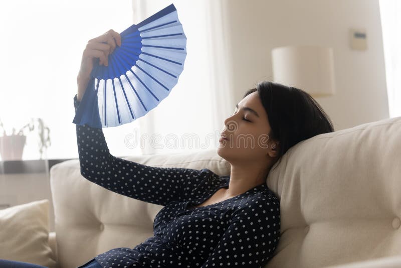 Unwell Asian girl feel overheated wave using hand fan