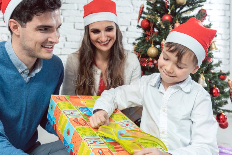Unwrapping χριστουγεννιάτικο δώρο παιδιών με την οικογένειά του στοκ φωτογραφίες Unwrapping χριστουγεννιάτικο δώρο παιδιών με την οικογένειά του στοκ φωτογραφίες