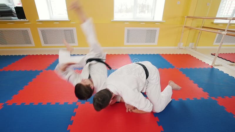 Uomini atletici impegnati in arte marziale degli aikidi Un uomo afferra il suo oppositore e lo getta sul pavimento