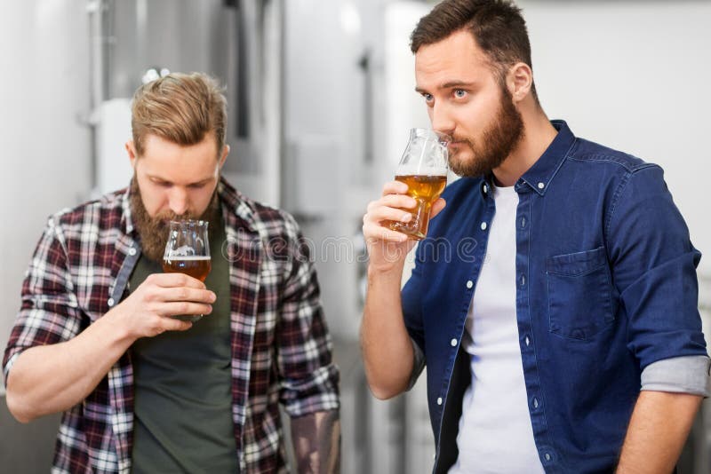 Uomini che bevono e che provano la birra del mestiere alla fabbrica di birra immagini stock libere da diritti Uomini che bevono e che provano la birra del mestiere alla fabbrica di birra immagini stock libere da diritti