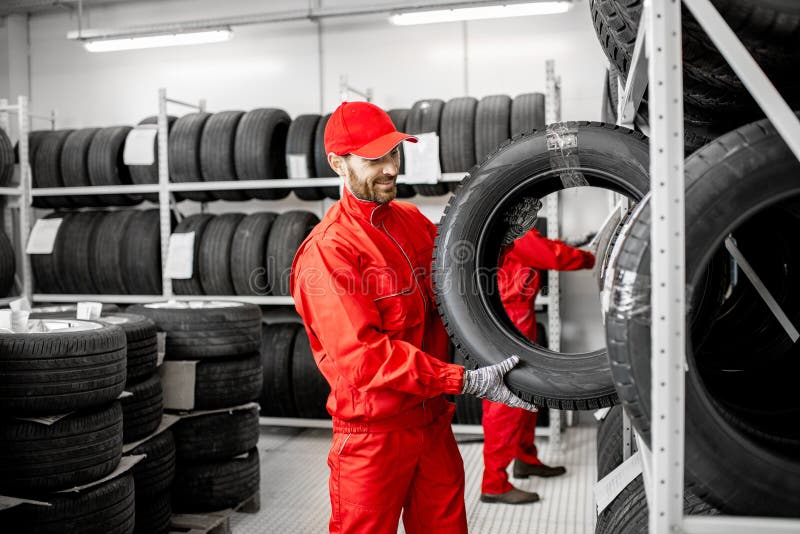 Uomini che lavorano nel magazzino con le gomme immagini stock Uomini che lavorano nel magazzino con le gomme immagini stock