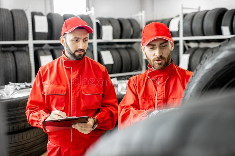 Uomini che lavorano nel magazzino con le gomme fotografia stock libera da diritti Uomini che lavorano nel magazzino con le gomme fotografia stock libera da diritti