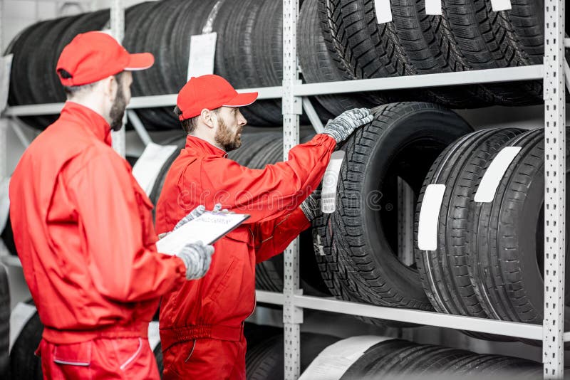 Uomini che lavorano nel magazzino con le gomme fotografia stock libera da diritti Uomini che lavorano nel magazzino con le gomme fotografia stock libera da diritti