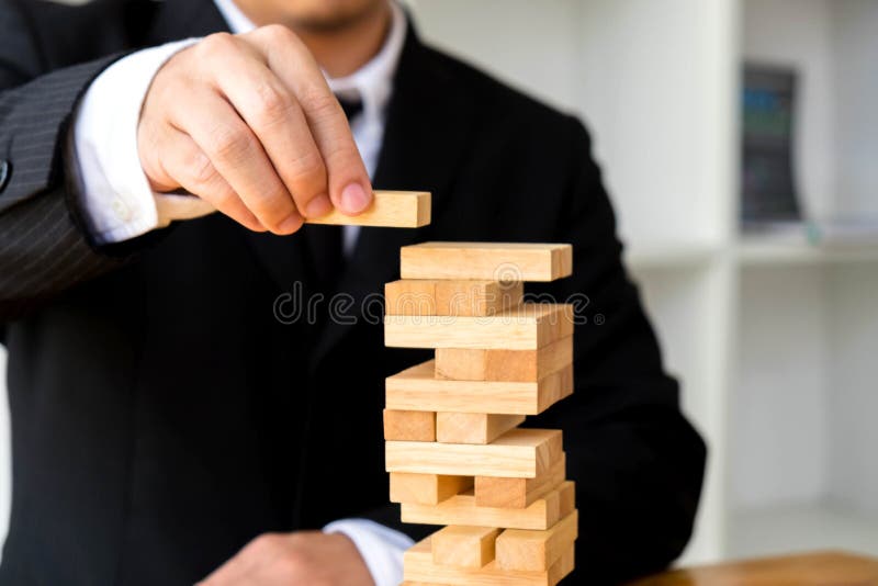 Uomini d'affari che selezionano i blocchetti del dominoe per riempire i domino mancanti fotografia stock Uomini d'affari che selezionano i blocchetti del dominoe per riempire i domino mancanti fotografia stock