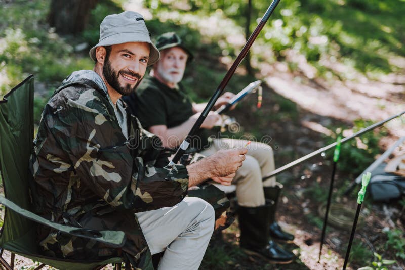 Uomo adulto allegro che pesca con suo padre pensionato immagini stock Uomo adulto allegro che pesca con suo padre pensionato immagini stock