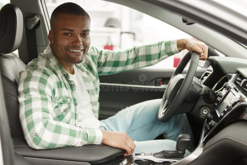 Uomo africano bello che sceglie nuova automobile alla gestione commerciale fotografia stock Uomo africano bello che sceglie nuova automobile alla gestione commerciale fotografia stock
