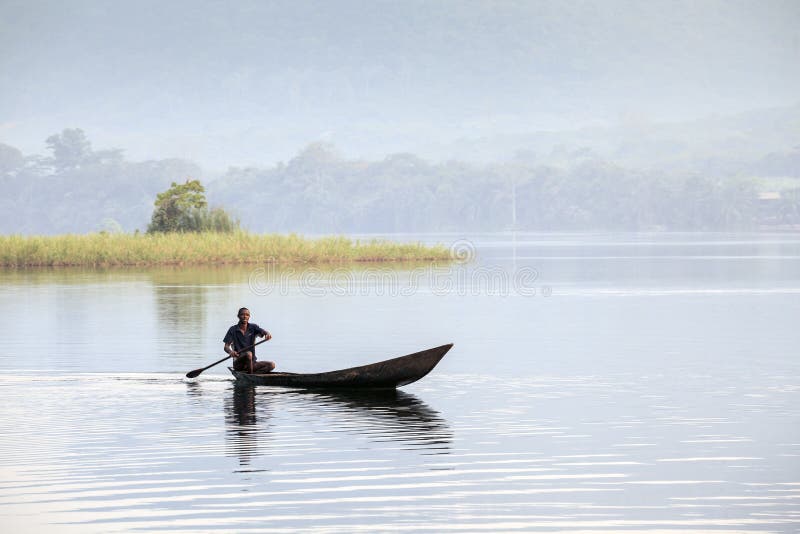 Uomo africano che guida una canoa immagine stock Uomo africano che guida una canoa immagine stock