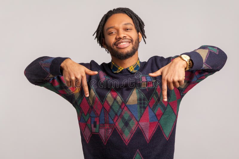 Uomo africano lieto allegro con i dreadlocks d'avanguardia che indica le dita per prestare la sua attenzione ad annunciare blogger immagine stock