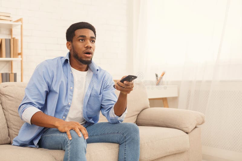 Uomo afroamericano che guarda TV a casa, spazio della copia fotografie stock libere da diritti Uomo afroamericano che guarda TV a casa, spazio della copia fotografie stock libere da diritti