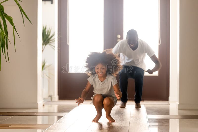 Uomo afroamericano felice che gioca gioco divertente con la figlia a casa immagini stock libere da diritti Uomo afroamericano felice che gioca gioco divertente con la figlia a casa immagini stock libere da diritti