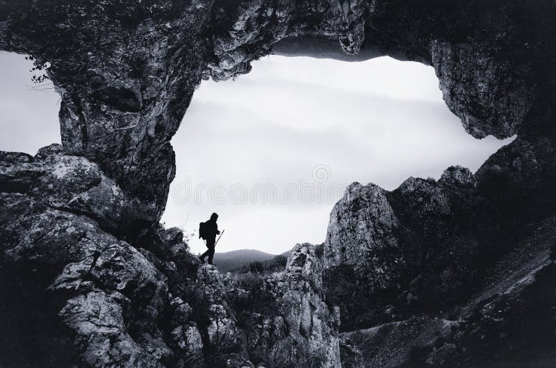 Uomo all'entrata della caverna con le scogliere giganti immagini stock Uomo all'entrata della caverna con le scogliere giganti immagini stock