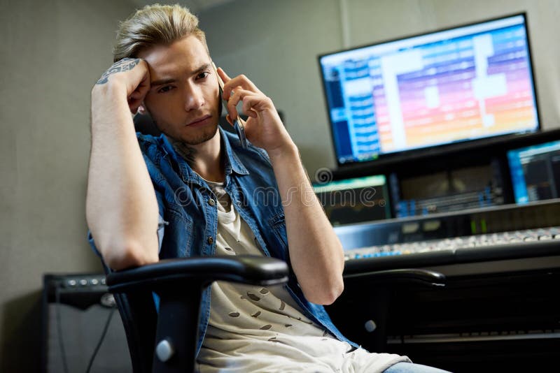 Uomo alla moda che parla sul telefono in studio immagini stock Uomo alla moda che parla sul telefono in studio immagini stock