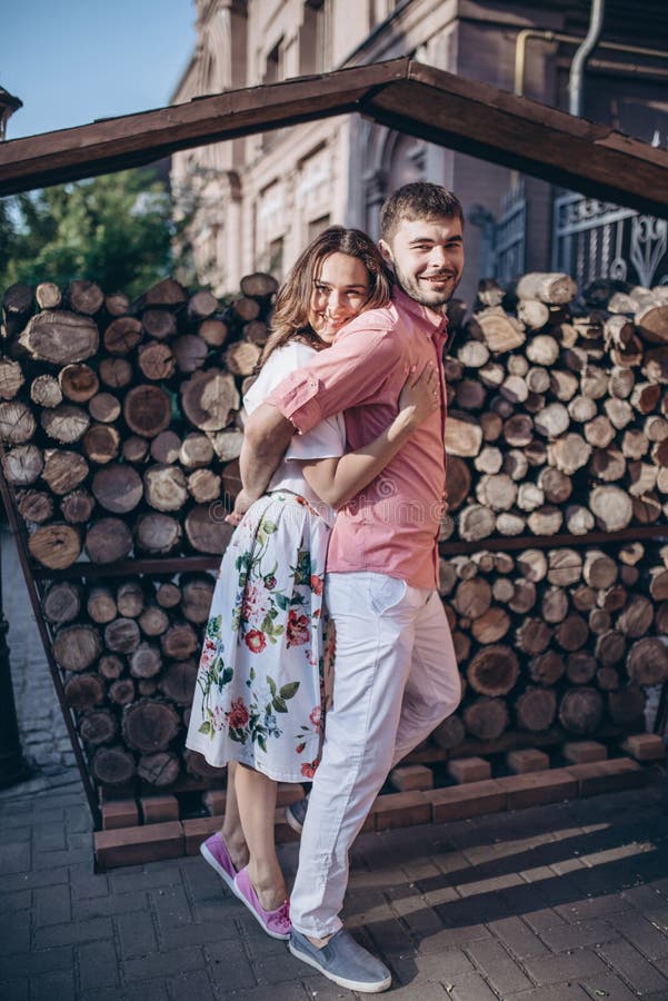 Uomo alla moda ed abbraccio felice della donna alla luce su fondo della parete di legno della legna da ardere Le coppie felici ha immagini stock Uomo alla moda ed abbraccio felice della donna alla luce su fondo della parete di legno della legna da ardere Le coppie felici ha immagini stock