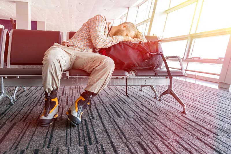 Uomo annullato di volo che dorme sui suoi bagagli di viaggio fotografie stock Uomo annullato di volo che dorme sui suoi bagagli di viaggio fotografie stock