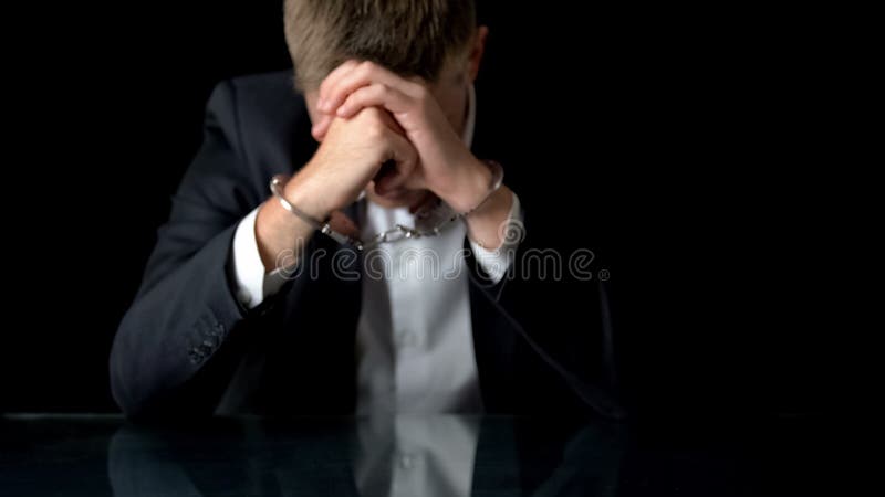 Uomo ansioso di affari in manette che si siedono sul posto di lavoro, commercio illegale, mafia immagine stock libera da diritti Uomo ansioso di affari in manette che si siedono sul posto di lavoro, commercio illegale, mafia immagine stock libera da diritti