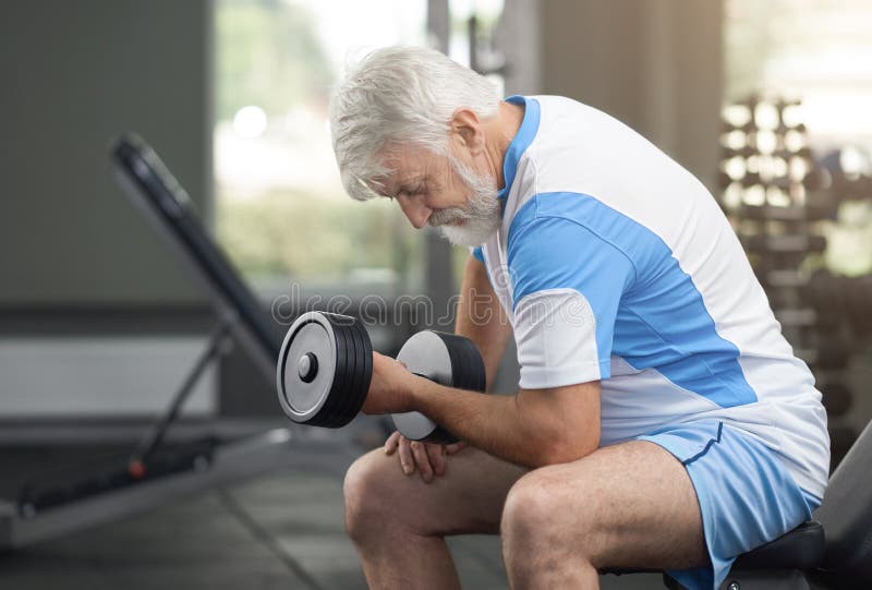 Uomo anziano adatto che risolve con le teste di legno in palestra fotografia stock Uomo anziano adatto che risolve con le teste di legno in palestra fotografia stock