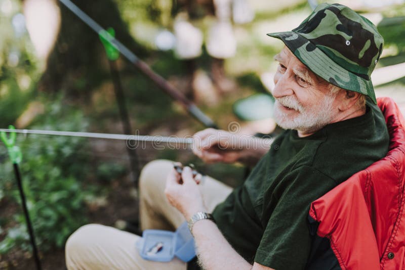 Uomo anziano allegro che gode della pesca nel fine settimana fotografia stock Uomo anziano allegro che gode della pesca nel fine settimana fotografia stock