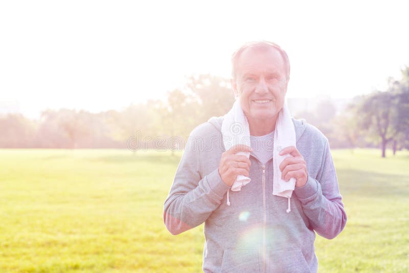 Uomo in asciugamano della tenuta degli abiti sportivi in parco il giorno soleggiato fotografia stock Uomo in asciugamano della tenuta degli abiti sportivi in parco il giorno soleggiato fotografia stock