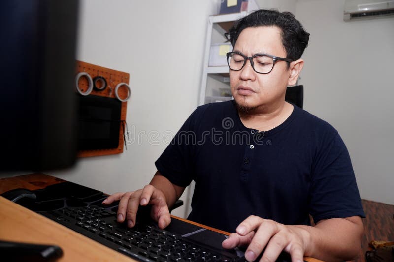 Uomo asiatico che batte computer su computer da casa freelancer che lavora in modalità remota online concetto di lavoro espression fotografia stock libera da diritti