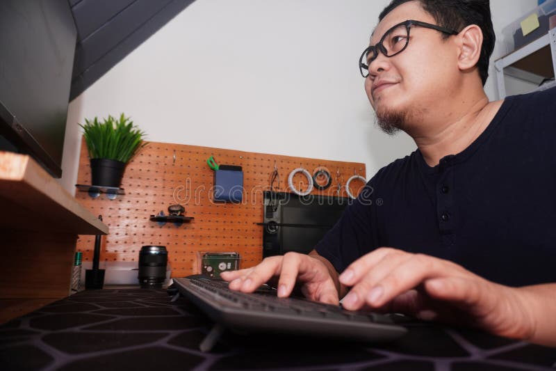 Uomo asiatico che batte il computer del pc da freelancer che lavora in remoto online e concetto di lavoro felice espressione sorri fotografia stock