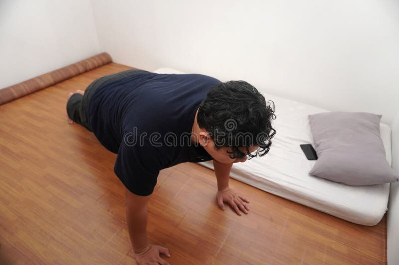 Uomo asiatico che fa flessioni nella sua stanza da letto dopo essersi svegliato al mattino immagini stock libere da diritti