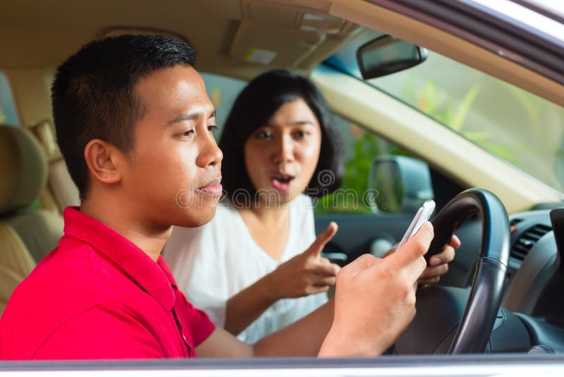 Uomo asiatico che texting mentre guidando immagine stock Uomo asiatico che texting mentre guidando immagine stock