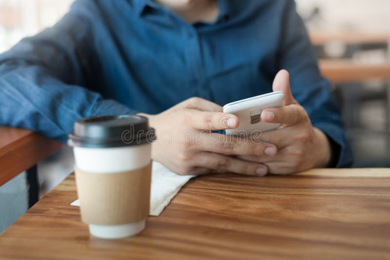 Adult Asian freelance businessman using smartphone for social network while sitting in coffee shop on weekend. Relax lifestyle with coffee. Adult Asian freelance businessman using smartphone for social network while sitting in coffee shop on weekend. Relax lifestyle with coffee