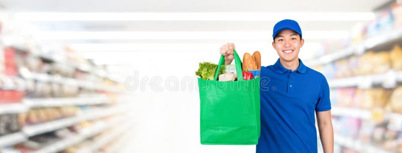 Smiling handsome Asian man holding grocery shopping bag in supermarket banner background with copy spce for food delivery service concept. Smiling handsome Asian man holding grocery shopping bag in supermarket banner background with copy spce for food delivery service concept